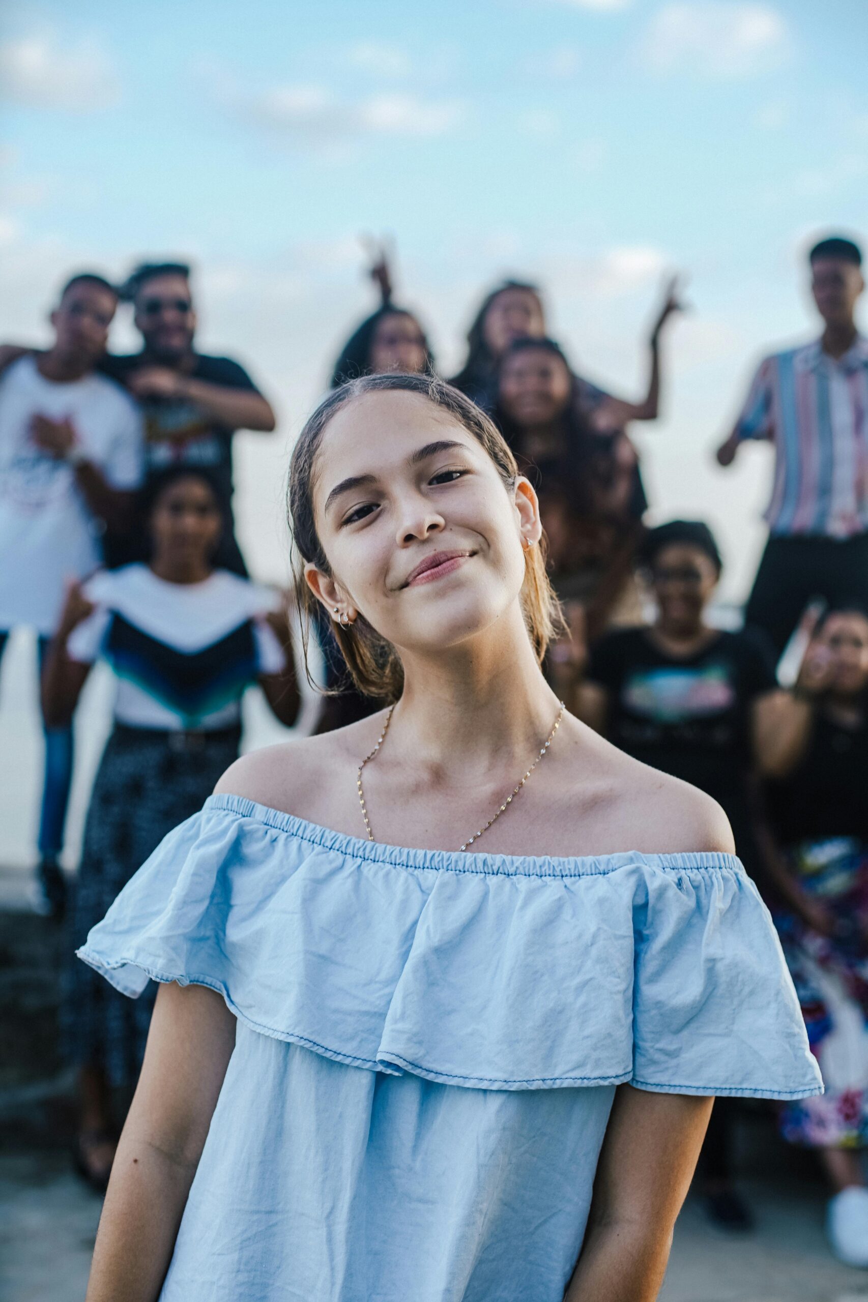 A cheerful teenage girl posing with friends in an outdoor setting, creating a joyful and lively atmosphere.